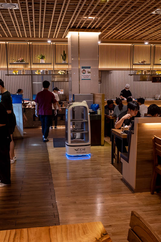 Korea for the 4th time - May and June 2022 - Not a great pic, but that thing with the blue light is a robot. It brings you your food to your table. I presume it is a roomba, and also vacuums as i