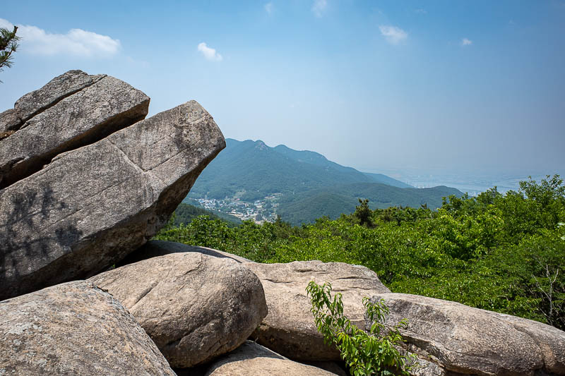 Korea-Busan-Hiking-Geumjeong - Rocks and a tiny glimpse of Gimhae, the city on the far side of this mountain range.