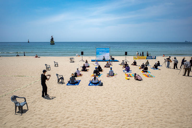 Korea-Busan-Beach-Haeundae - There is loud music blasting, jet skis, wannabe pop stars, and this meditation session. I am mildly amuse that the chief meditator is sitting in front
