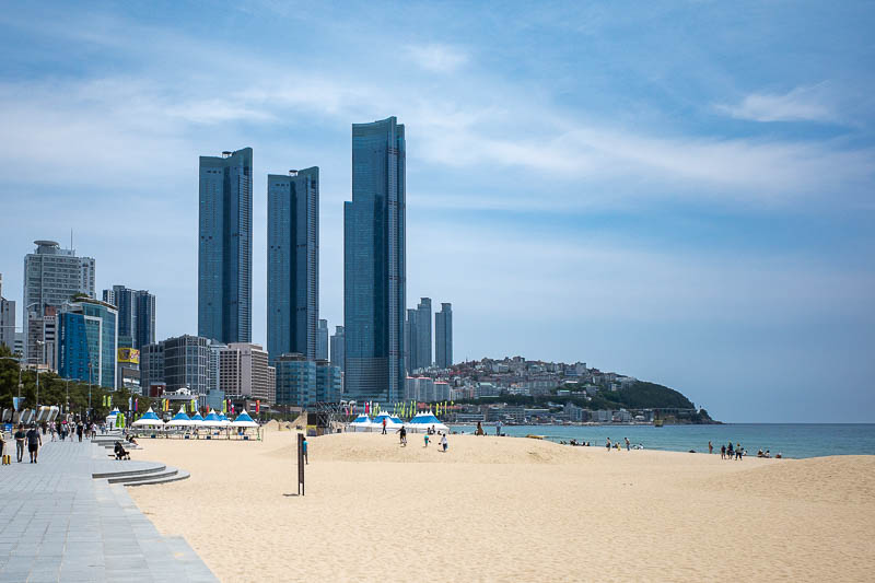 Korea-Busan-Beach-Haeundae - Beach, with houses going up the hill and huge towers.
