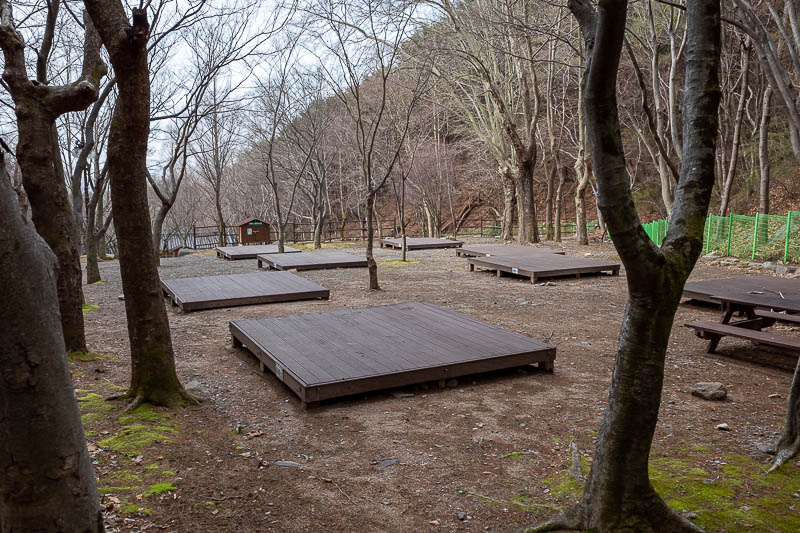 More of the same of Korea - March and April 2024 - You start by going past some camp sites. Korean camp sites are a flat wooden deck, you pitch your tent on the deck. There were tents here last year bu