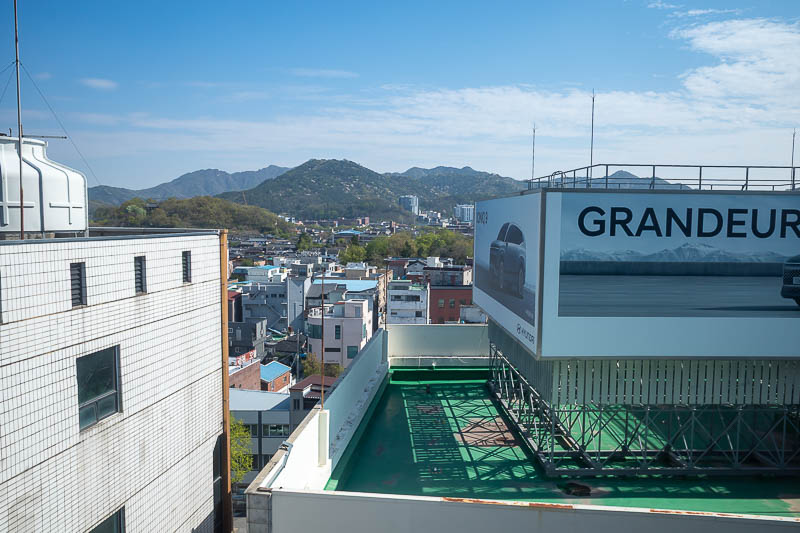 Korea-Daejeon-Jeonju-KTX - And finally my view, of an advertising sign for a Hyundai mainly, but also some distant mountains I will soon see up close.