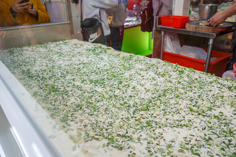 A full lap of Taiwan in March 2017 - Taiwan night markets are famous for their food, this is a giant spring onion pancake. The cook pulls bits off and adds other stuff before cooking in e