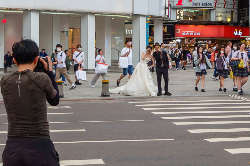 Taiwan-Taipei-Ximending-Pasta - First sighting of the bride. Yes, they are holding instant cameras pretending to take photos. Yes, the groom does appear to be wearing an Indiana Jone