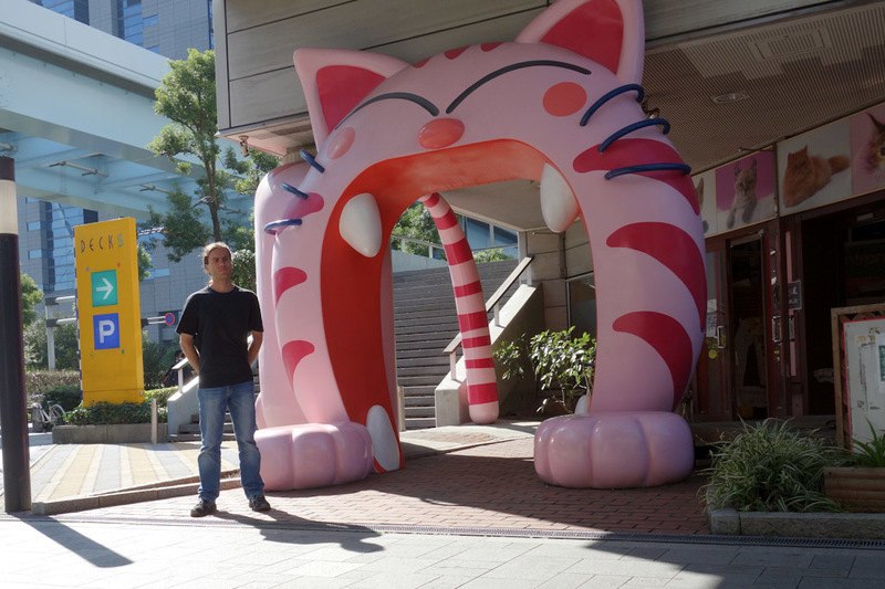 I flew all the way to Tokyo and back for the weekend - Here I am, in Japan, standing in front of a cat cafe, which is guarded by a giant pink cat. This area, called Odaiba which is an island of reclaimed t